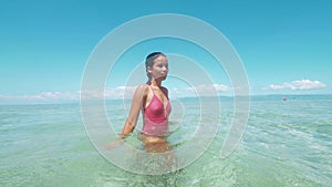 Charming asian woman enjoys bathing and splashing water in clear ocean.