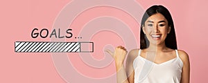 Charming Asian woman pointing at GOALS loading progress bar on pink studio background, panorama. Collage