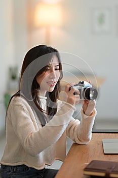 Charming asian young female taking photo by vintage retro camera in modern coffee shop