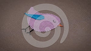 Charming Avian Art: Hand Stitched Bird Adorns Pink Cloth