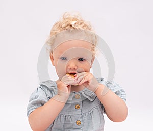 Charming baby girl bites a cookie