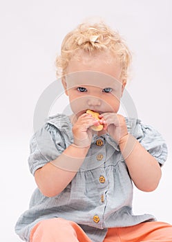 Charming baby girl bites a cookie