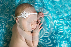 Charming baby in headband sleeping on stomach