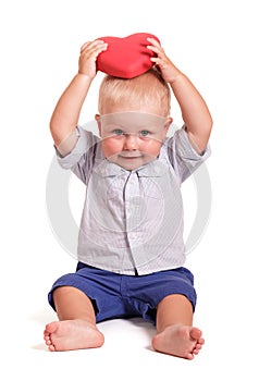 Charming baby holding a red heart in hands over head