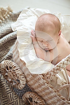 Charming baby, sleeping in wicker stroller, cream