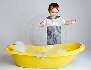 Charming baby standing near bathtub