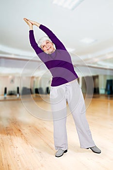 Charming beautiful elderly woman doing exercises while working out playing sports