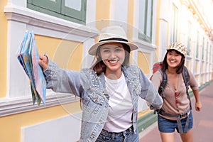 Charming beautiful traveler woman is holding handâ€™s friend and inviting friend to some touristic place. They look happiness and