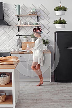 Charming beautiful woman holding a bottle of milk. Beautiful girl is preparing breakfast at modern cozy kitchen.