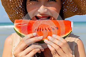 Charming beautiful young woman eating watermelon to cool down and quench her thirst in summer season at beach. It look juicy and