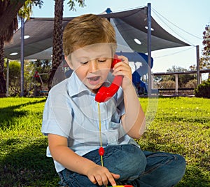 Charming blond boy speaks on telephone