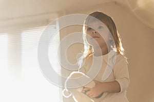 Charming blonde baby with a toy in the morning