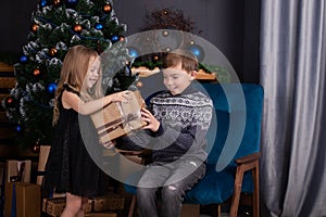 charming blonde little boy and girl near christmas tree. brother and sister celebrating new year