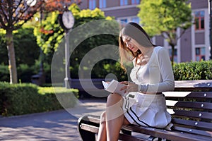 Charming bookworm: Young lady enjoys good weather, reading novel on park bench amid nature. Cherishing perfect reading moment in t