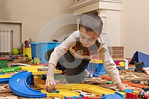 charming boy plays on the floor with car track. Child playing with toys indoor. Activities for kids at home. toddler