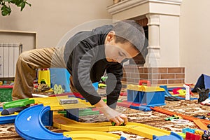 charming boy plays on the floor with car track. Child playing with toys indoor. Activities for kids at home. toddler