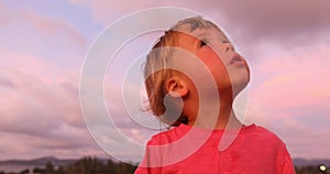 Charming boy in sunset looking around