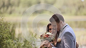 Charming bride with a bouquet and her fiance together on nature. Tenderness of relations. Kiss. Happy together. Wedding