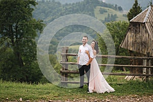 Charming bride hug her handsome groom in mountains. Beautiful wedding couple walk. Green gackground