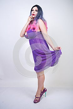 Charming buxom girl stands in a purple transparent nightgown lingerie on a white background in the Studio