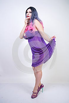 Charming buxom girl stands in a purple transparent nightgown lingerie on a white background in the Studio