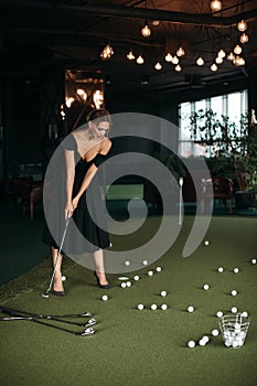 Charming caucasian lady poses for the camera and plays golf, picture isolated on dark blur background