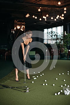 Charming caucasian lady poses for the camera and plays golf, picture isolated on dark blur background