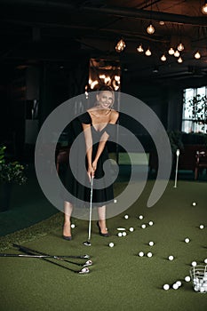 Charming caucasian lady poses for the camera and plays golf, picture isolated on dark blur background