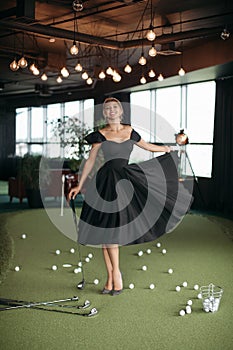 Charming caucasian lady poses for the camera and plays golf, picture isolated on dark blur background