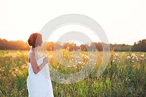 Charming caucasian woman 30-35 years old in a field at sunset in summer