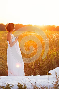 Charming caucasian woman 30-35 years old in a field at sunset in summer