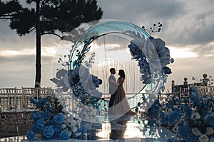 Charming couple in love in a chic banquet room in the open air against the backdrop of the sea on a gala wedding day