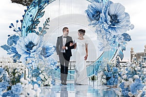 Charming couple in love in a chic banquet room in the open air against the backdrop of the sea on a gala wedding day