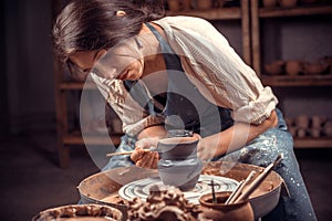 Charming craftsman master works with clay on a potter& x27;s wheel. Ceramics art concept .