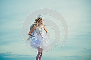 Charming curly little girl in white dress and wings - angel cupid girl. Enjoying magic moment. Pretty white little girl