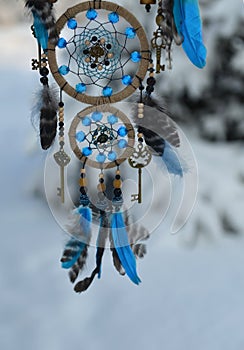Charming decoration of dreamcatcher with blue feathers and key agains snow landscape. photo