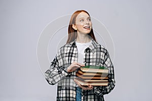 Charming dreamy young woman college student holding book and looking away on isolated background