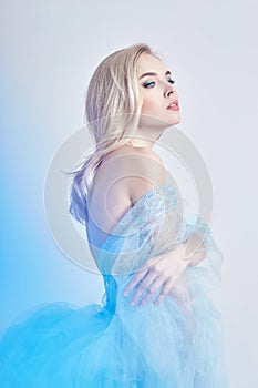 Charming fairy woman in a blue cotton dress and long hair, mysterious, delicate blonde girl with perfect skin and makeup