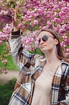 charming fashionable woman in blooming sakura park