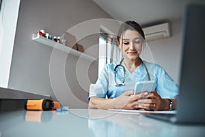 Charming female doctor using mobile phone in clinic