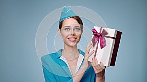 A charming flight attendant holds gift box in her hands. Duty free.