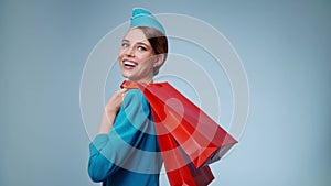 A charming flight attendant holds shopping bags in her hands. Duty free.