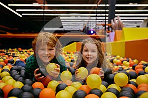 Charming funny children lying in dry pool with colorful balls