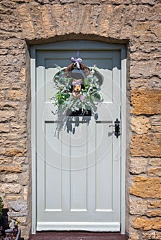 Charming garland with straw squirrel surrounded by grasses and flowers hanging on wooden  front door