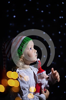 Charming girl Christmas Santa hat black background with star lanterns. portrait todller against starry sky.