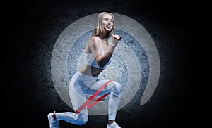 Charming girl does an exercise called lunges. Elastic band for training. The concept of fitness, bodybuilding and healthy