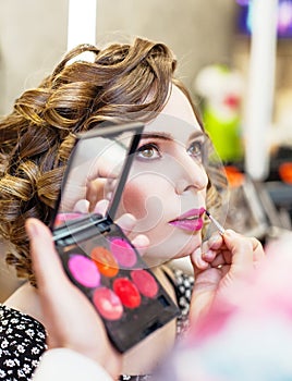 Charming Girl doing make-up in a beauty salon.