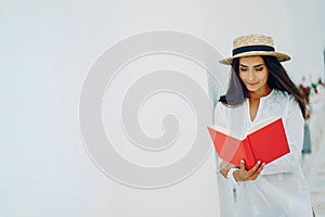 charming girl enjoys the sunny weather by the pool with a book