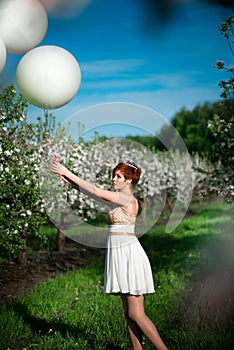 Charming girl holding white balloons looking sadly at them