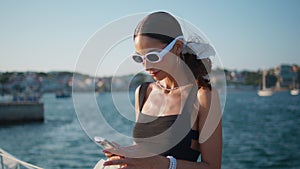 Charming girl looking smartphone screen at sunny seaside close up. Happy woman
